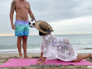 Mooie latina Alika Penagos probeert een yoga-video op het strand te doen