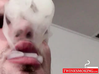 Tío flaco tatuado fumando y disparando semen en el suelo